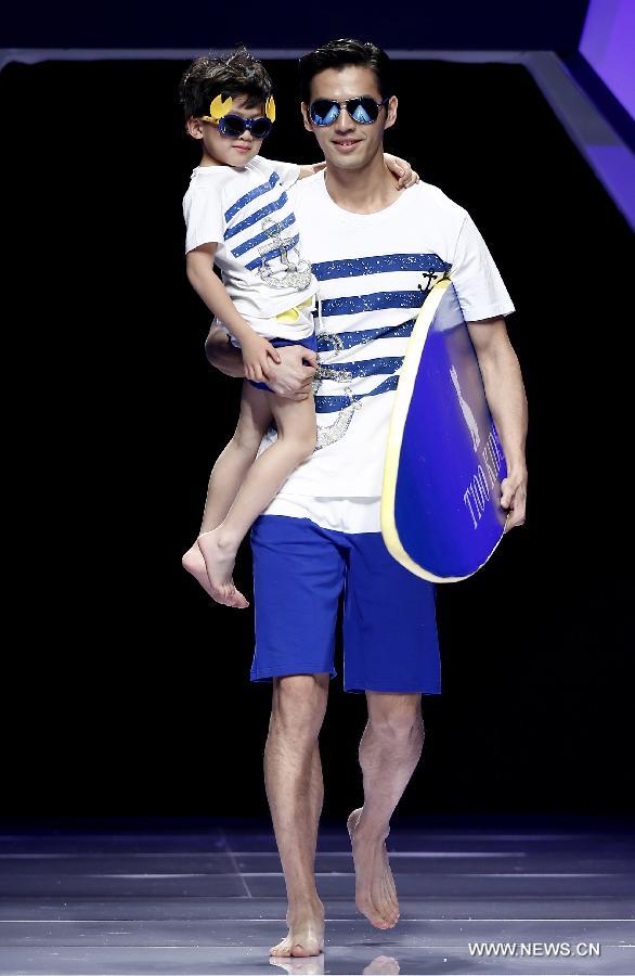 An adult and a child model present creations designed by Dong Wenmei during China Fashion Week in Beijing, capital of China, Oct. 29, 2014. [Xinhua]