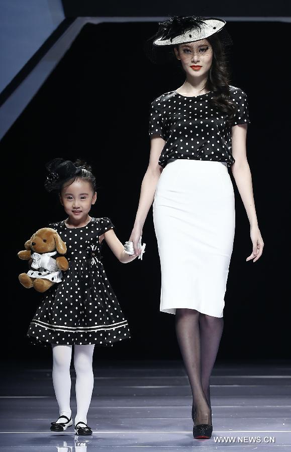 An adult and a child model present creations designed by Dong Wenmei during China Fashion Week in Beijing, capital of China, Oct. 29, 2014. [Xinhua]