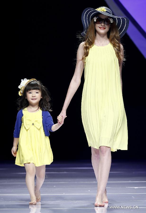 An adult and a child model present creations designed by Dong Wenmei during China Fashion Week in Beijing, capital of China, Oct. 29, 2014. [Xinhua]