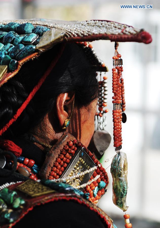 A woman presents Burang costume at Kegya Village in Burang County of Nagri Prefecture, southwest China's Tibet Autonomous Region, Oct. 23, 2014. Burang costume, which has a history of more than 1,000 years, is famous for its luxurious accessories. Hundreds of pieces of beeswax, numerous pearls and kallaties, bunchy red corals and delicate silver and gold decorations compose of priceless suite. Seven households at Kegya Village have preserved seven suits of Burang costumes handed down by ancestors. [Xinhua]