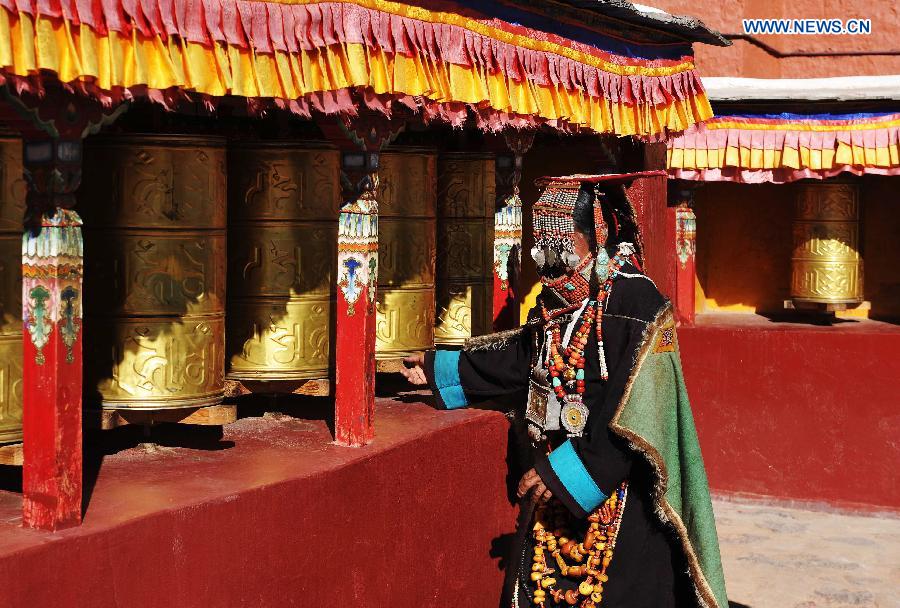 A woman wearing Burang costume rotate prayer wheels at Kegya Village in Burang County of Nagri Prefecture, southwest China's Tibet Autonomous Region, Oct. 23, 2014. 