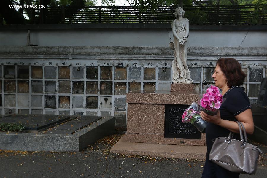 A woman holds flowers for her late relatives during the commemoration of the Day of the Dead, at the Araca municipal cementery in Sao Paulo, Brazil, on Nov. 2, 2014. [Photo/Xinhua]