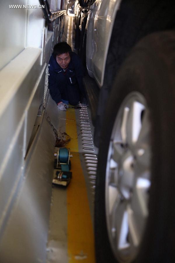 A worker fixes a car onto a carriage at Dahongmen Railway Station in Beijing, capital of China, Nov. 4, 2014. Beijing Railway Bureau has opened several special train routes for self-driving tourists during the vacation of the Asia-Pacific Economic Cooperation (APEC) Economic Leaders' Week, which will be held in Beijing from Nov. 5 to 11. [Photo/Xinhua]