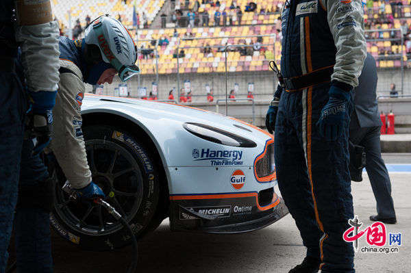 Pit garage workers of the Aston Martin Racing put on the tires to the racing vehicle prior to the the Six Hours of Shanghai, the China competition of the FIA World Endurance Championship (WEC) on Sunday, Nov. 2, 2012. [Photo by Chen Boyuan / China.org.cn]