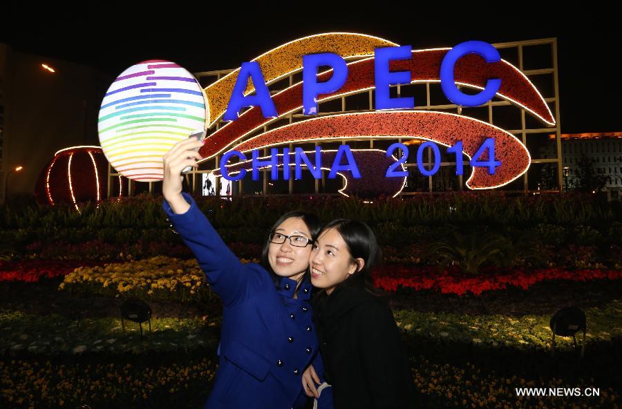 Two women take selfie in front of APEC illuminations in Beijing, capital of China, Nov. 4, 2014. From Nov. 4 to 11, the landscape lighting in Beijing will be decorated as in major festivals like the National Day. [Photo/Xinhua] 