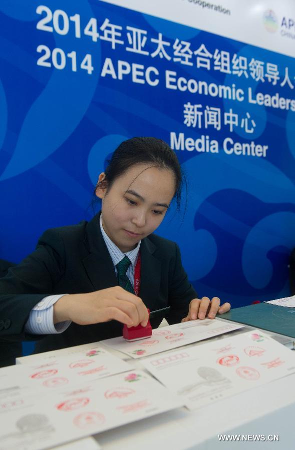 A staff member postmarks commemorative envelopes issued for the upcoming 22nd APEC Economic Leaders' Meeting (AELM) in Beijing, China, Nov. 5, 2014. [Photo/Xinhua]