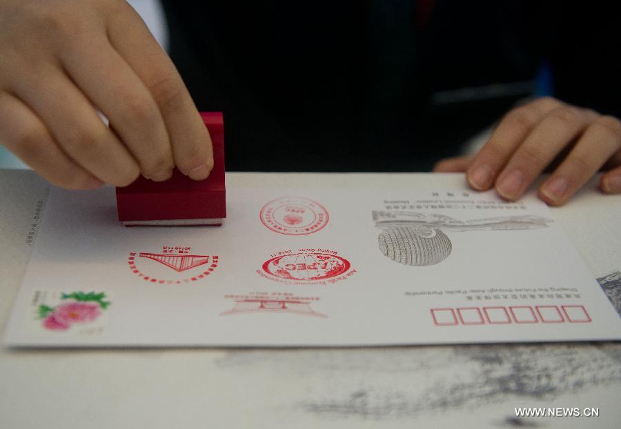 A staff member postmarks a commemorative envelope issued for the upcoming 22nd APEC Economic Leaders' Meeting (AELM) in Beijing, China, Nov. 5, 2014. [Photo/Xinhua]