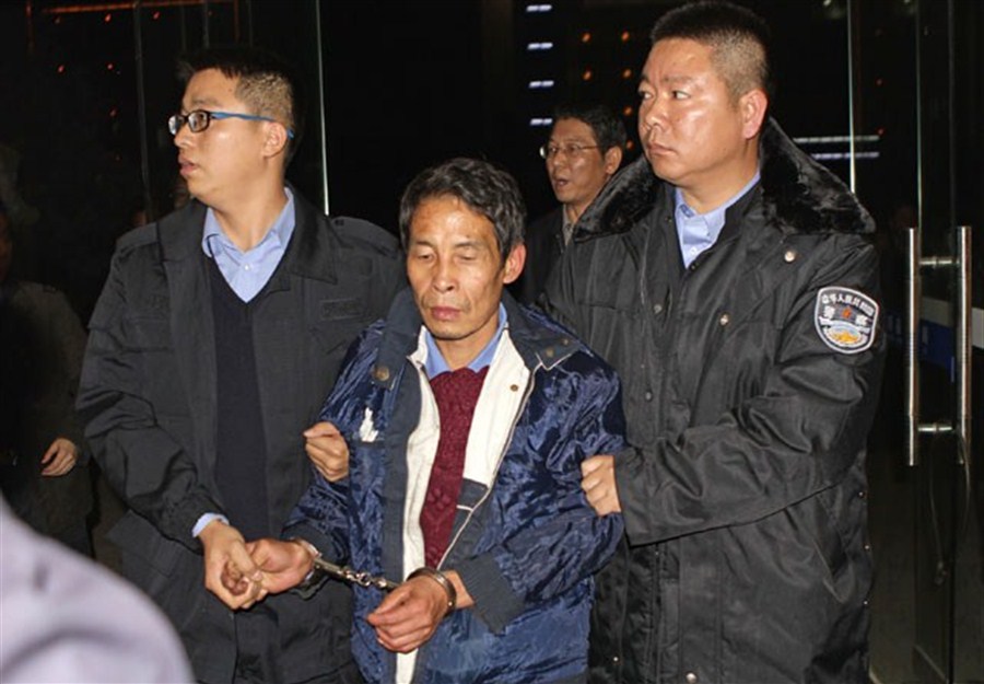 Police escort Zhang Yangxi after he was captured yesterday following a tip-off. He was named as the key suspect in an attack in Guixi City, Jiangxi Province, last Friday that left two schoolchildren dead and a third seriously injured. The children were on their way home from school.