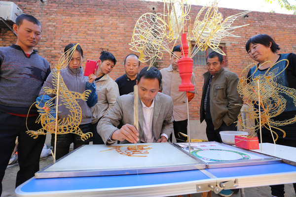 Liu Shengli displays his sugar art craftsman skills with his apprentices watching on the side.