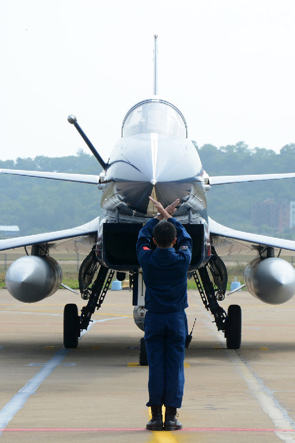 A member of the ground crew directs a J-10 jet fighter at the 10th China International Aviation and Aerospace Exhibition in Zhuhai, South China's Guangdong province on Nov 5, 2014. [Photo/Xinhua]