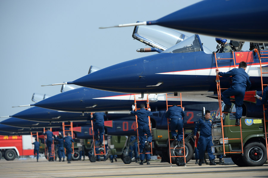 Crew members conduct maintenance checks on J-10 jet fighter before the a practice for a performance by the Bayi Aerobatic Team at the 10th China International Aviation and Aerospace Exhibition in Zhuhai, South China's Guangdong province on Nov 9, 2014. [Photo/Xinhua] 