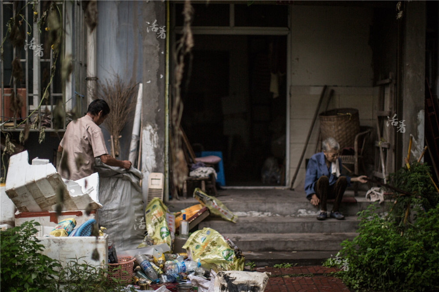 Mo Shunhai, 59, and his wife, 58, in front of their house in Luzhou city, Southwest China's Sichuan city. Mo plants vegetables around the house and collects garbage to support the family. They also receive retirement pensions and minimum social security payments. Zhou sits in silence for hours. [Photo/news.qq.com]