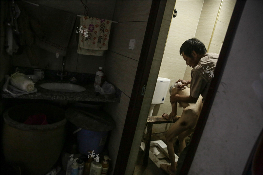 Mo helps his wife wash. She has bruises on her legs after sitting for so long.[Photo/news.qq.com]