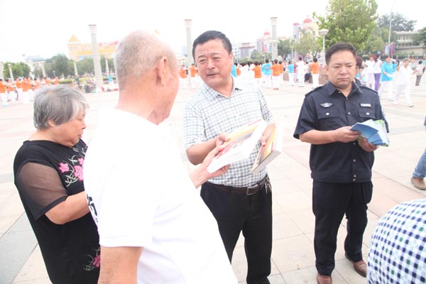 Li Chunyuan talks to people about environmental problems on the streets of Langfang, Hebei province, on a smoggy day while passing out his books for free to residents. [Photo provided to China Daily]