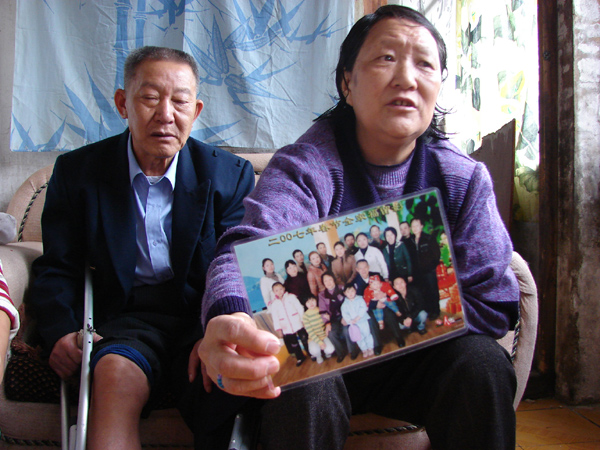 Yang Zongfa and his wife show a family photo in which his mother is sitting in the middle, in Liupanshui, Southwest China's Guizhou province, September 11, 2007.
