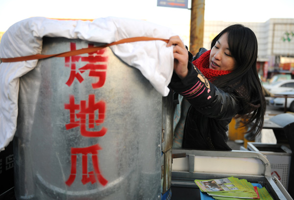 Wang Yanhong sells baked potatoes in a street in Jinan, Dec 1, 2014.