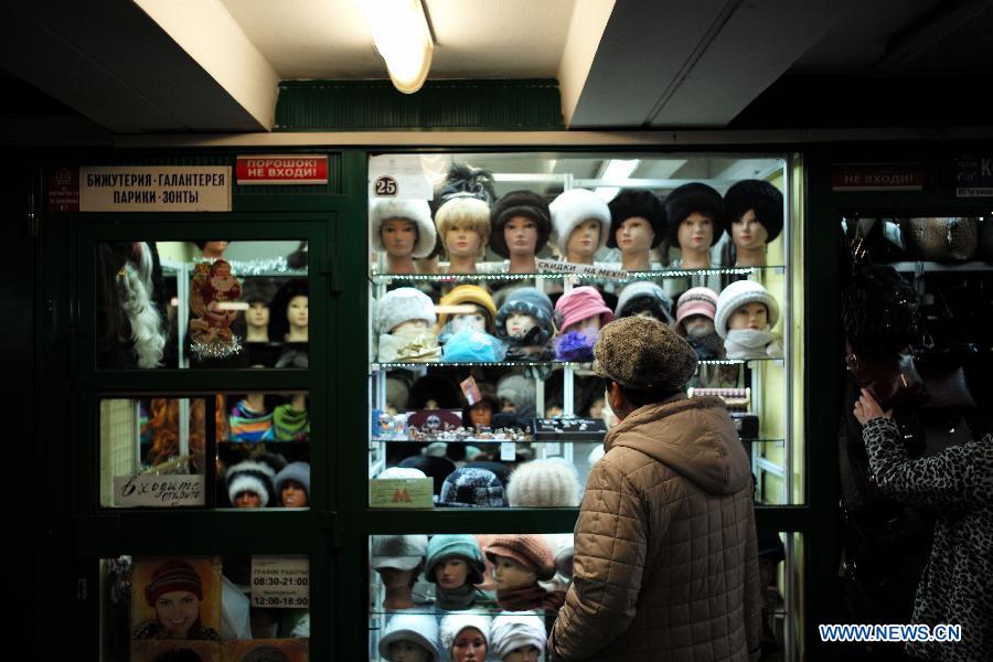 A woman stands in front of a hat booth in a passageway in Moscow, Russia, Dec. 17, 2014. Russian Prime Minister Dmitry Medvedev on Wednesday warned citizens and companies of attempting to make profit in the current unstable financial situation, calling the ongoing events at the currency market a 'game of emotions.' [Photo/Xinhua] 