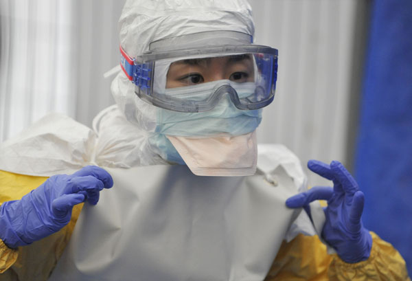 A volunteer learns to dress in a protection suit at a training center in Brussels. He will go to Africa to assist medical staff to fight against Ebola. [Photo/Xinhua] 