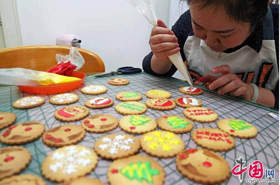 A cake maker puts Christmas-themed features on cookies in Zhengzhou City, Henan Province on Dec. 23, 2014. The store received a large number of orders for this kind of cookies in the run-up to Christmas. [China.org.cn]