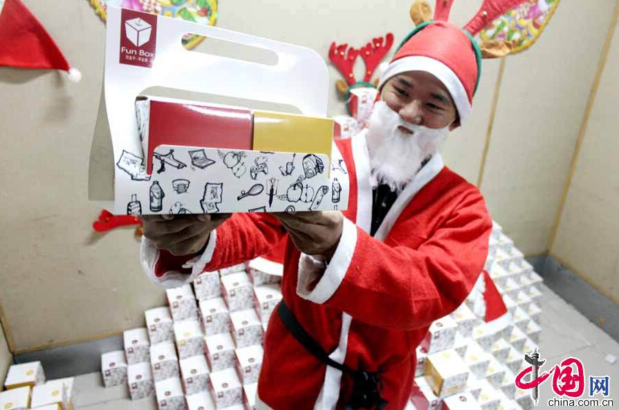 A box wrapping design exhibition was held at Academy of Arts in LiaochengUniversity, Shandong Province, on Dec. 23, 2014. Eight students designed these boxes and piled them into a small pyramid with a dressed-up 'Santa Claus' standing nearby to explain their design vision. According to the organizers, students can learn how to design and sell the boxes to enterprises. [China.org.cn]