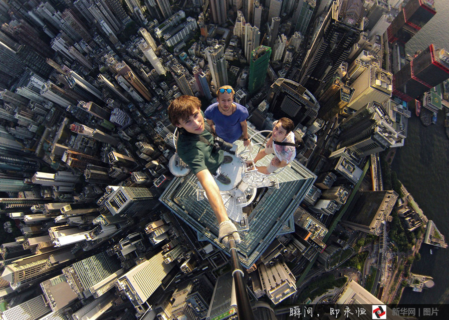 Three adventurers take photo of themselves using selfie device at the top of a skyscraper in Hong Kong, China. [Photo/Xinhuanet]