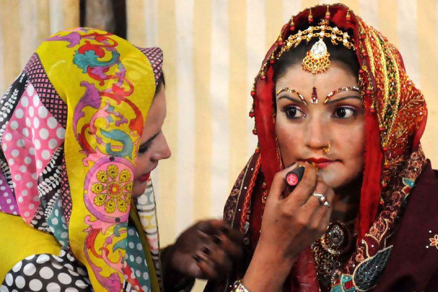 A bride (R) gets ready during a group wedding ceremony in southern Pakistani port city of Karachi, on Jan. 2, 2015. A total of 50 couples attended a group wedding organized by the Pakistan Hindu Council. [Photo/Xinhua]
