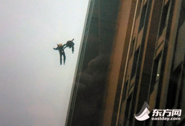 A netizen in Shanghai snaps the shot that two young firefighters are holding each other’s hands when being pushed out from the 13th floor of a residential building by heat waves on 1 May, 2014. A massive fire broke out in the building in the afternoon, causing the deaths of two young firefighters: Qian Lingyun, aged at 23, and Liu Jie, aged at 20. Both joined the army in December 2012. [Photo: eastday.com] 