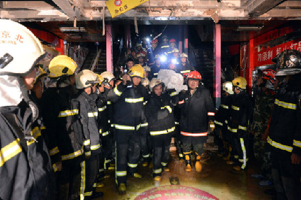 Soldiers carry the bodies of two firefighters out of a shopping mall in Shijingshan District, west Beijing that caught fire early Friday morning, October 11, 2013. They are Liu Hongkui, 28, and Liu Hongkun, 35. No other casualties were reported. [Photo: guancha.com]