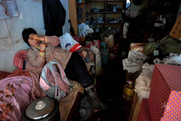 A woman lies on her bed in a room full of necessities and jade articles. Many jade workers live and work in the same room at Xingfu village in Bengbu city, east China's Anhui province. [Photo/qq.com]