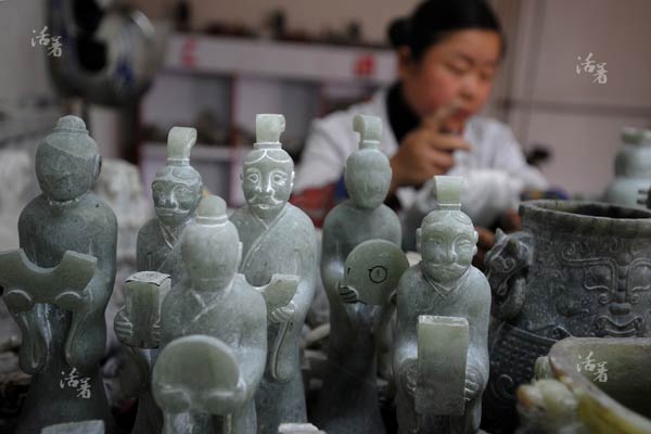 A jade worker works on blank versions of antique jade at Xingfu village in Bengbu city, east China's Anhui province. The practice is a basic process of the mass production of antique jade. [Photo/qq.com]