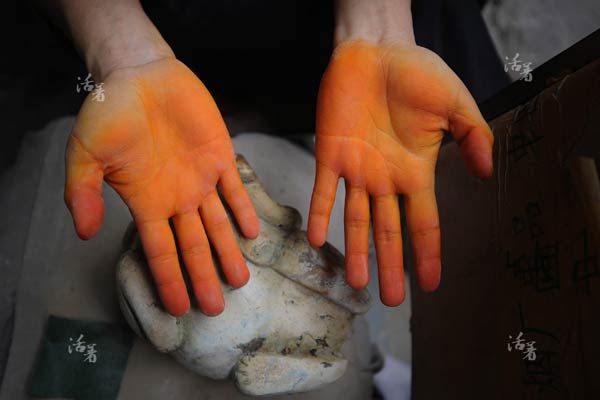 A jade worker&apos;s hands are colored with the chemical materials used for producing antique jade. [Photo/qq.com]