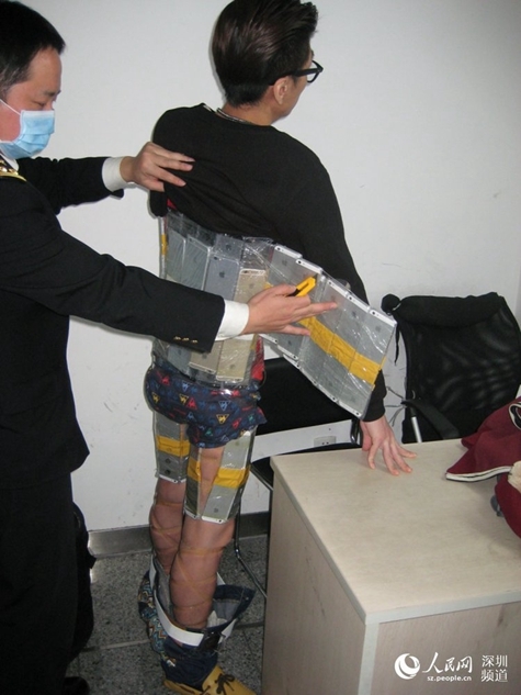 A Hong Kong smuggler hides 94 iPhones under his clothes in order to get the products into the Chinese mainland on Jan. 11, 2015. The male passenger caught the attention of customs staff for his stiff and slow movements. [Photo: people.cn] 