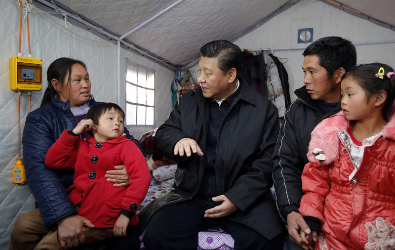 Chinese President Xi Jinping (C) pays a visit to a family affected by the 6.5 magnitude earthquake in August last year in Ganjiazhai Village, Ludian County, southwest China's Yunnan Province on Jan 19, 2015. A temporary camp was set up in the village for those displaced by the quake. [Photo: Xinhua]