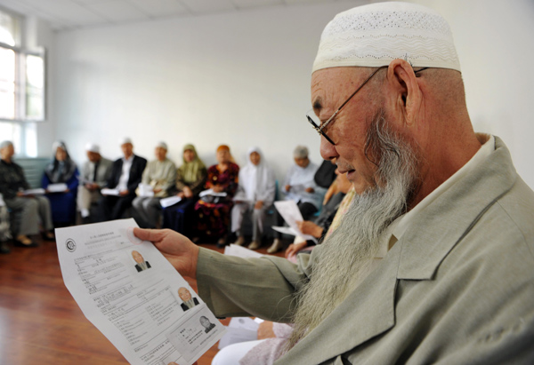 A Uygur man reviews papers related to his pilgrimage. [Photo/Xinhua]