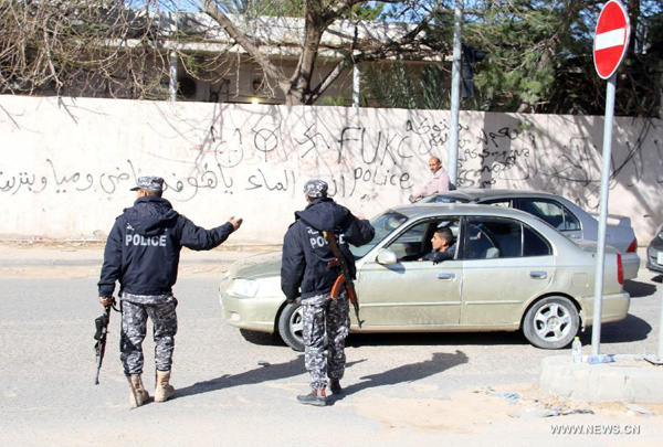 Two policemen check the cars passing by in Tripoli, Libya, on Jan. 25, 2015. More security forces were deployed in Tripoli to curb the recent waves of kidnapping and attacks. The deputy foreign minister in Libya's internationally recognized government, Hassan Alsaghir, was kidnapped by unknown gunmen on Jan. 25 in the eastern city of Beida, according to Libyan government sources. [Photo/Xinhua]