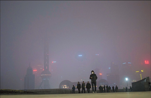 A man wearing a mask at the Bund yesterday. The Lujiazui skyscrapers across the Huangpu River are almost obscured by the heavy smog. [Agencies]
