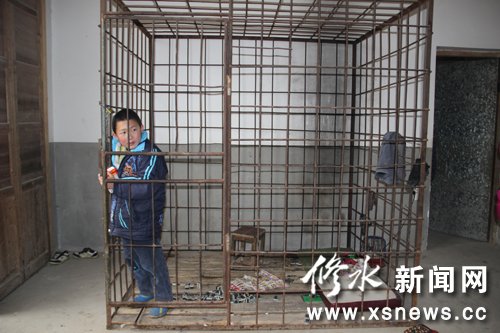 Xiao Wang, a 12-year-old boy who suffers Attention deficit hyperactivity disorder (ADHD), plays inside an iron cage.[Photo/xsnews.cc] 