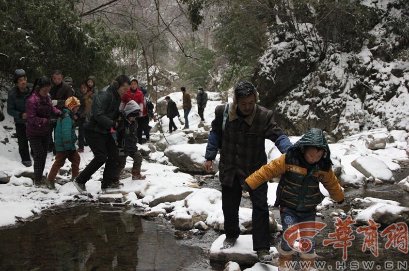 Elementary students and their parents walk on a snow-covered mountain road to school in Guanyin township, Zhenba county, Northwest China’s Shaanxi province, Jan 29, 2015.[Photo/HSW.cn]