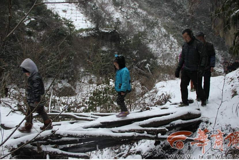Elementary students and their parents walk on a snow-covered mountain road to school in Guanyin township, Zhenba county, Northwest China’s Shaanxi province, Jan 29, 2015.[Photo/HSW.cn]