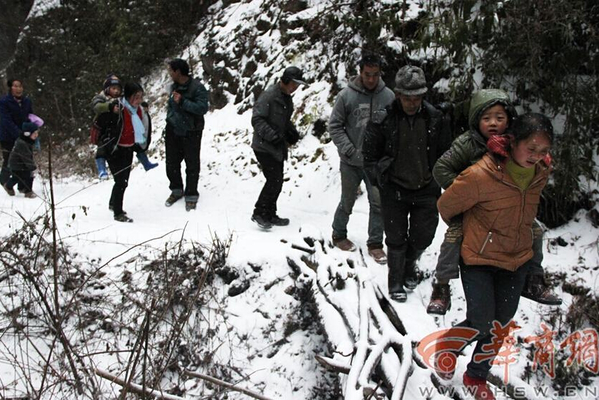 Elementary students and their parents walk on a snow-covered mountain road to school in Guanyin township, Zhenba county, Northwest China’s Shaanxi province, Jan 29, 2015.[Photo/HSW.cn] 