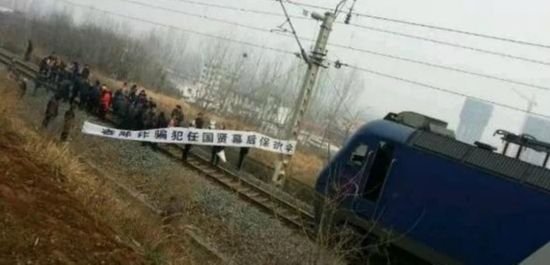 People stand in front of a train at the railway station in Xixia county, central Henan province, Feb 2, 2015. [Photo/People.cn]