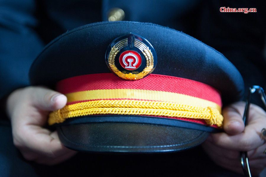 Song Jian holds his cap, saying the badge on the cap means honor to him. [Photo by Chen Boyuan / China.org.cn]