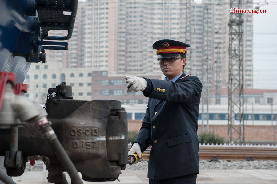 Song Jian performs a visual inspection before the two drivers board the locomotive. [Photo by Chen Boyuan / China.org.cn]