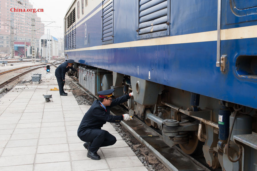 The locomotive&apos;s driver and chief engineer Ding Hailong (L) uses a spanner to tighten loose bolts while Song Jian, who is a deputy driver, is only authorized to perform the visual inspection. [Photo by Chen Boyuan / China.org.cn]