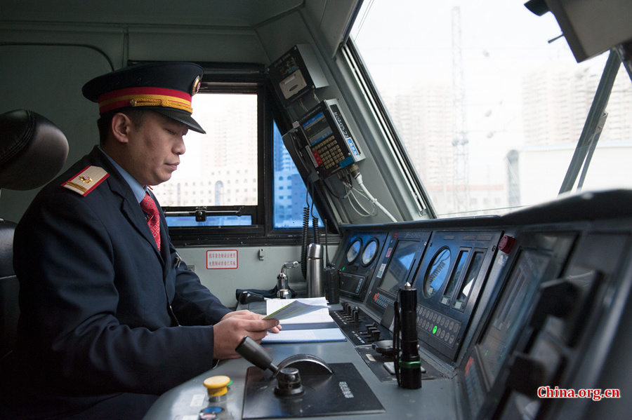 The locomotive&apos;s chief engineer and driver Ding Hailong reads the daily memo once again before setting the locomotive in motion. [Photo by Chen Boyuan / China.org.cn]