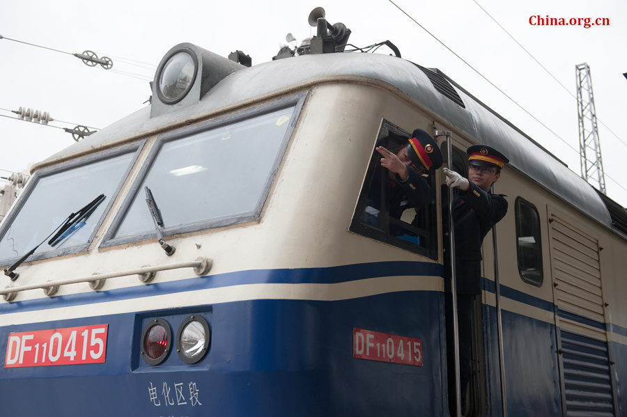 Song Jian (R) and Ding Hailong both confirm the signal visually ahead before the locomotive is set in motion. They say the double confirmation is to ensure complete safety. [Photo by Chen Boyuan / China.org.cn]