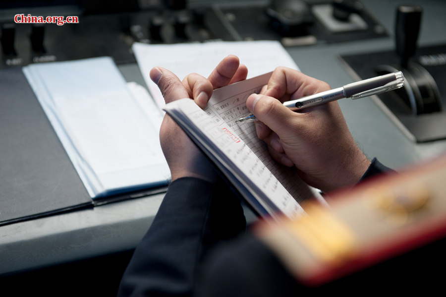 The locomotive&apos;s chief engineer and driver Ding Hailong writes in the log book. [Photo by Chen Boyuan / China.org.cn]