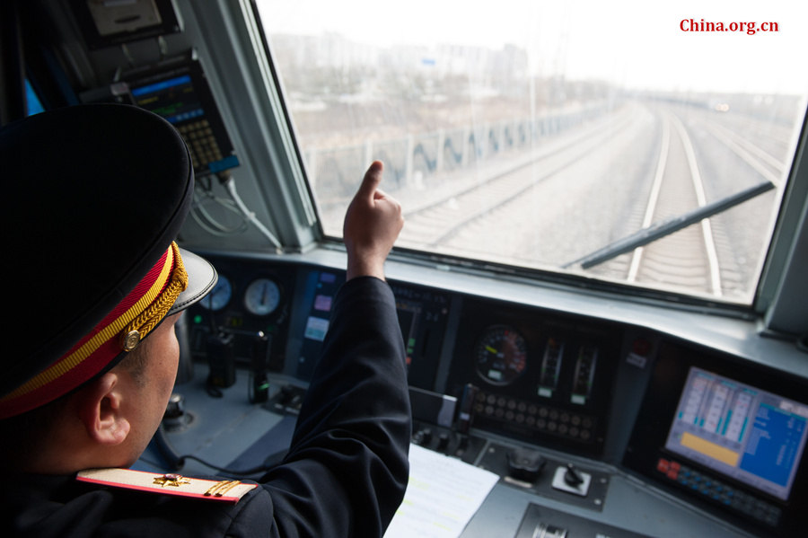 The train&apos;s chief engineer Ding Hailong uses hand gestures to confirm he has received Song Jian&apos;s notice for a railway signal ahead in the distance. [Photo by Chen Boyuan / China.org.cn]