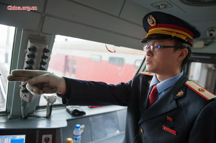 Song Jian points to a signal in the distance to keep himself alert. He says he performs such gestures more than one thousand times each day. [Photo by Chen Boyuan / China.org.cn]