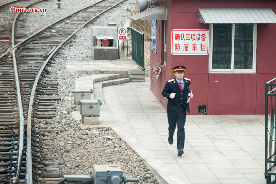 Song Jian runs back to the locomotive after getting the clearance from a checkpoint before their train departs from the station with up to 2,000 passengers. [Photo by Chen Boyuan / China.org.cn]